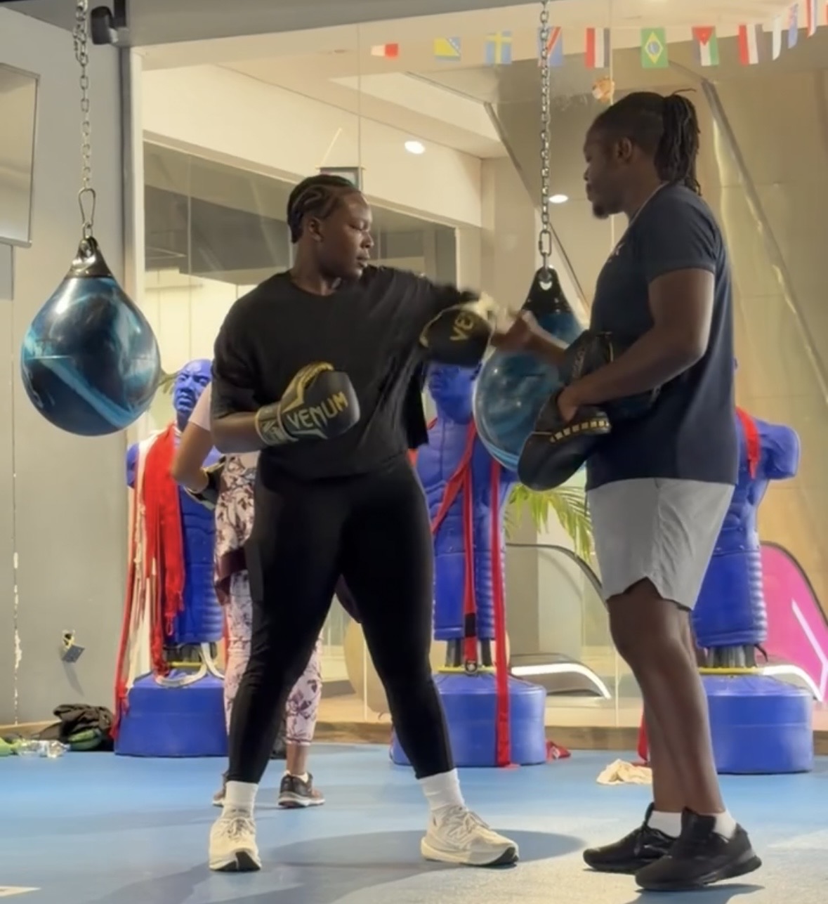 Khadijat throwing a punch at focus mitts held by a coach in a boxing gym