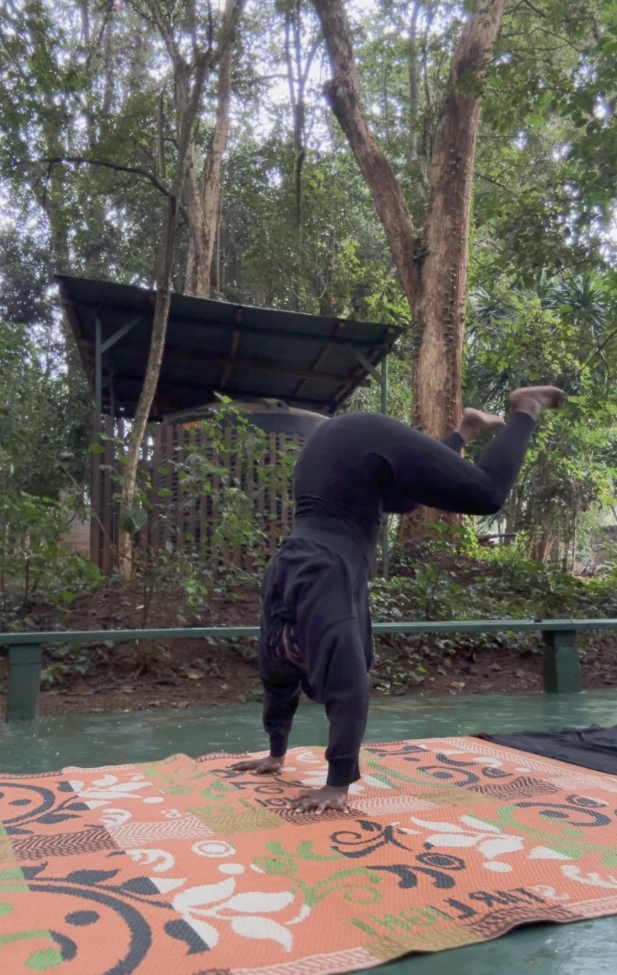 Khadijat doing a handstand on a patterned mat outdoors in Karura Forest, Kenya